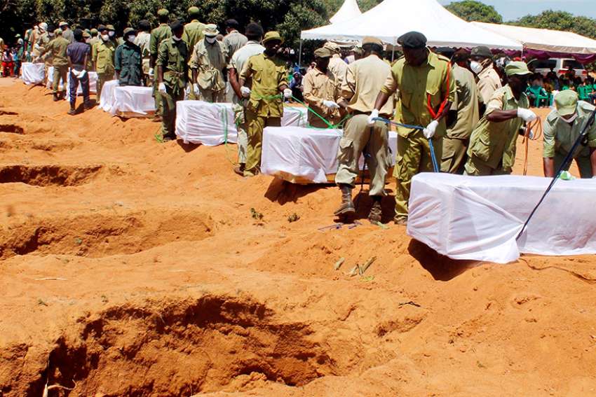 Tanzanian security agents in Ukara bury coffins Sept. 23 after a ferry overturned two days earlier in Lake Victoria.