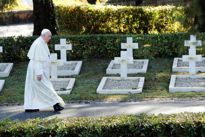 Pope Francis walks by graves at the French Military Cemetery before celebrating Mass for the feast of All Souls at the cemetery in Rome Nov. 2, 2021.