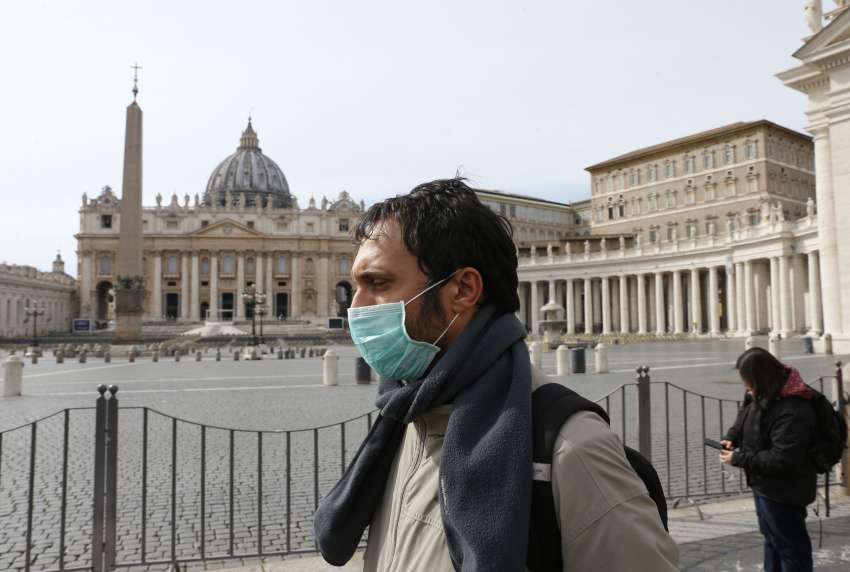 A man wearing a mask for protection from the coronavirus passes an empty St. Peter&#039;s Square at the Vatican March 10. The Vatican has closed St. Peter&#039;s Square and Basilica to tourists March 10 through April 3 in co-operation with Italian emergency procedures aimed at preventing the spread of the coronavirus. 