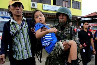 government soldier carries a girl who was rescued along with 20 other residents as government troops continued to fight Islamic militants May 31 in Marawi, Philippines.