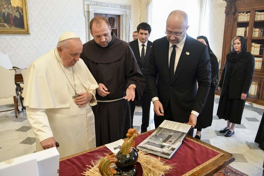 Ukrainian Prime Minister Denys Shmyhal gives Pope Francis a book during a meeting in the library of the Apostolic Palace at the Vatican April 27, 2023. The book contained photos documenting the damage inflicted on Ukraine by Russian bombing.