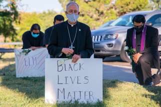 Bishop Mark J. Seitz of El Paso, Texas, kneels at El Paso’s Memorial Park holding a “Black Lives Matter” sign on June 1, 2020, a week after George Floyd was killed by a policie officer.