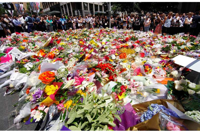 Members of the public look at thousands of floral tributes placed Dec. 16 near the Sydney cafewhere hostages were held for more than 16 hours. An Irish priest based in Sydney said he was amazed at how many people turned to prayer during the deadly siege.