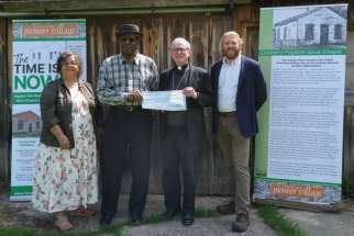 London Bishop Ronald Fabbro, third from left, presents a $5,000 cheque to restore London’s Fugitive Slave Chapel to steering committee members Christina Lord and Carl Cadogan (to his right) and Tom Peace, chair of the Fanshawe Pioneer Village Board.