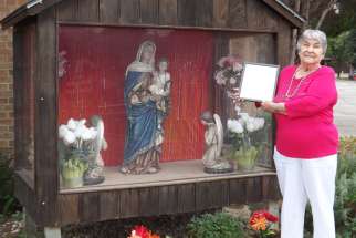 Jennie McRae poses at Sts. Martha and Mary Parish in Mississauga with the letter she received from Cardinal Thomas Collins after completing her decade-long trek around the vast territory of the archdiocese to visit all its churches.