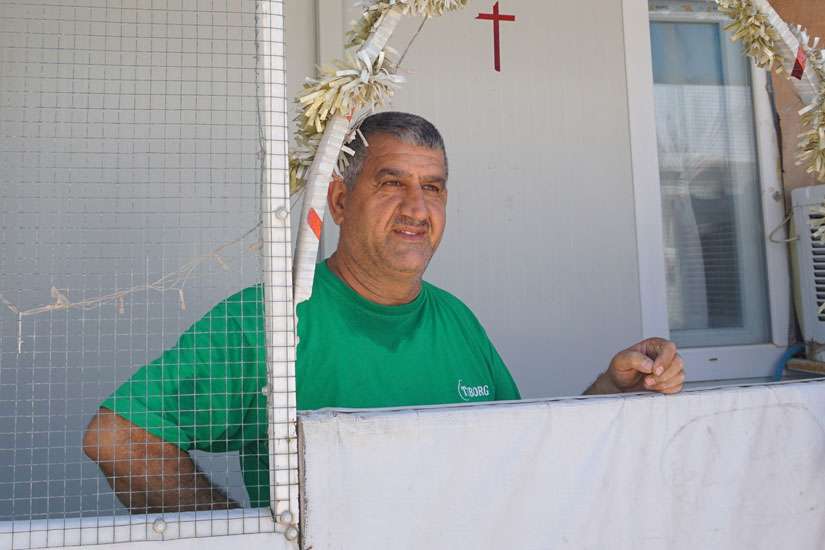 An Iraqi Christian spruces up his shelter July 24 with a cross and other Christian symbols at the the Ashti camp for internally displaced Iraqis in Ainkawa. Some 7,000 Christians, mainly Catholics, were forced to escape the Islamic State assault on Mosul and their surrounding villages two years ago and fled to Ainkawa, a Christian enclave of the Kurdish capital, Irbil.