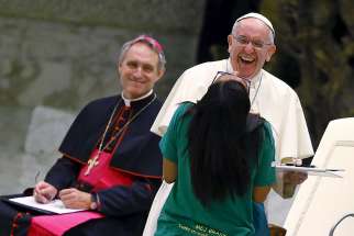Pope Francis smiles as he greets a young woman during a special audience with members of the Eucharistic Youth Movement in Paul VI hall at the Vatican Aug. 7.