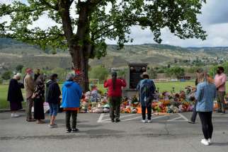 A small group visits a makeshift memorial on the grounds of the former Kamloops Indian Residential School in Kamloops, British Columbia.