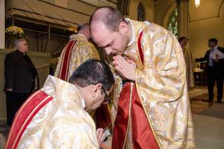 Toronto’s newest priests, Fr. Julien Malenfant, blessing another priest at left, and Fr. Tom Kluger, were ordained April 30.