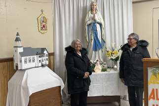 Elders and church leaders Annabella Iahtail and Francis Hookimaw beside a model of the St. Francis Xavier Church in Attawapiskat in northern Ontario, which burned down in 2021.
