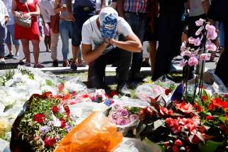 A man prays in front of a makeshift memorial July 15 in Nice, France, as people pay tribute near the scene where a truck ran into a crowd killing more than 80 people the previous evening.