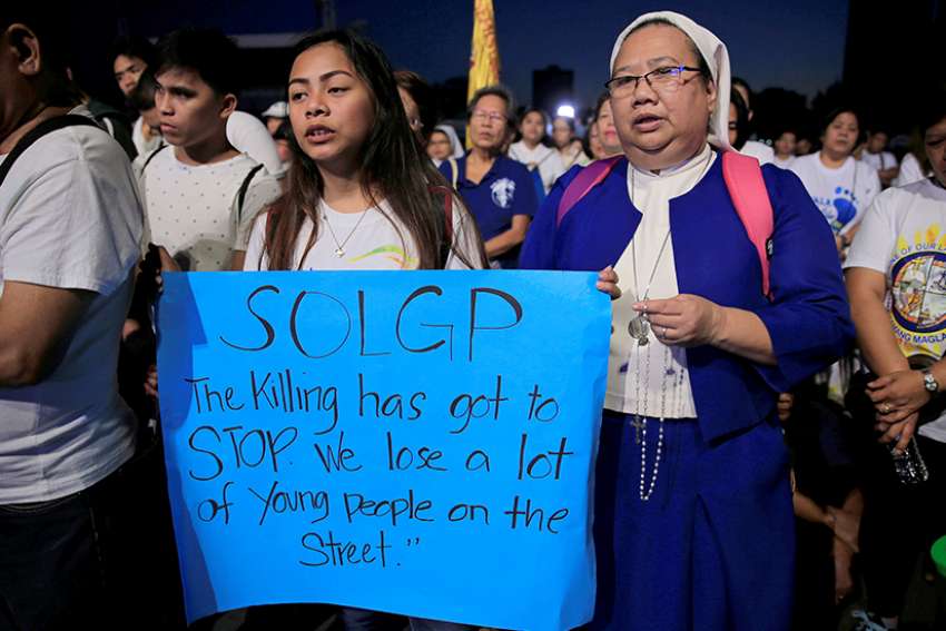 A student and woman religious display a sign as they participate in a procession to protest plans to reimpose death penalty and intensify the drug war during &quot;Walk for Life&quot; in late February in Manila, Philippines.