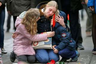 A woman consoles her children at a street memorial March 23 following bomb attacks in Brussels. Three nearly simultaneous attacks March 22 claimed the lives of dozens and injured more than 200. 