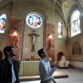 Ryan Alemao, a first-year seminarian at St. Augustine’s Seminary, describes the designs of stained glass windows in the chapel as fellow first-year seminarian, his younger brother Favin, looks on.