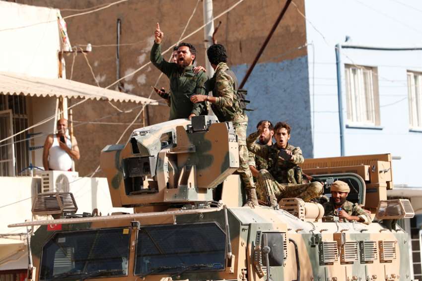 Members of Syrian National Army, known as the Free Syrian Army, react as they drive on top of an armored vehicle Oct. 11, 2019, in the Turkish border town of Ceylanpinar. Dozens of advocacy organizations participating in the International Religious Freedom Roundtable called on U.S. President Donald Trump &quot;not to abandon Christians, Yazidis and Kurds&quot; in the Syrian border region that Turkey is bombing.