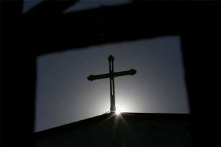 A cross atop a Catholic church is silhouetted in Tianjin, China.
