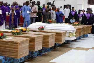 Flowers lie on caskets during a funeral Mass in the parish hall of St. Francis Xavier Church in Owo, Nigeria, June 17, 2022, for some of the 40 victims killed in a June 5 attack by gunmen during Mass at the church.
