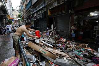 A man cleans his store Aug. 24 after super Typhoon Hato hit in Macau. Parishes in Macau Diocese held special Masses Aug. 28 for those killed and affected by the super typhoon. 