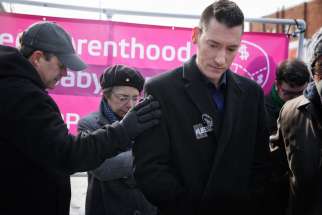 A man comforts David Daleiden, founder of the Center for Medical Progress, during a prayer and protest rally outside of the new Planned Parenthood building in Washington Jan. 21, the day before the annual March For Life. Daleiden&#039;s organization is being sued by the National Abortion Federation over a series of undercover videos on Planned Parenthood.