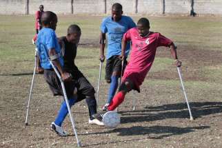 Wilfrid Macena, in red, who lost a leg in the Jan. 12, 2010, earthquake, battles for the ball during an early morning practice in 2011 on a soccer field in Port-au-Prince, Haiti. Macena and two other members of a Haitian amputee soccer team gave Pope Francis a soccer jersey and ball signed by team members during a Jan. 10 papal audience marking the fifth-year anniversary of the magnitude-7 earthquake.
