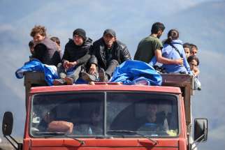 Refugees from the Nagorno-Karabakh region in Azerbaijan ride in a truck upon their arrival at the border village of Kornidzor, Armenia, Sept. 27. Tens of thousands of ethnic Armenians, most of them Christian, are fleeing the enclave Armenians call Artsakh following a defeat by surrounding Azerbaijan forces.