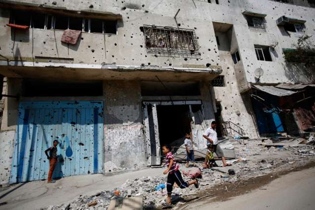 A Palestinian boy runs next to destroyed buildings in Gaza City Aug. 28.  In a written message to a world summit of religious leaders, Pope Francis said that war is just &quot;senseless slaughter&quot; and should never be seen as inevitable or a done deal.