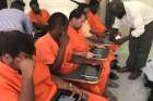 Inmates at the Belize Central Prison use tablets to access a remote learning system.
