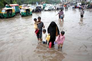 A family wades through a flooded street during heavy rains in New Delhi, India, Aug. 6, 2019. Catholic churches and other institutions opened their doors to people stranded in Mumbai and surrounding areas because transportation routes were blocked by high water and debris.