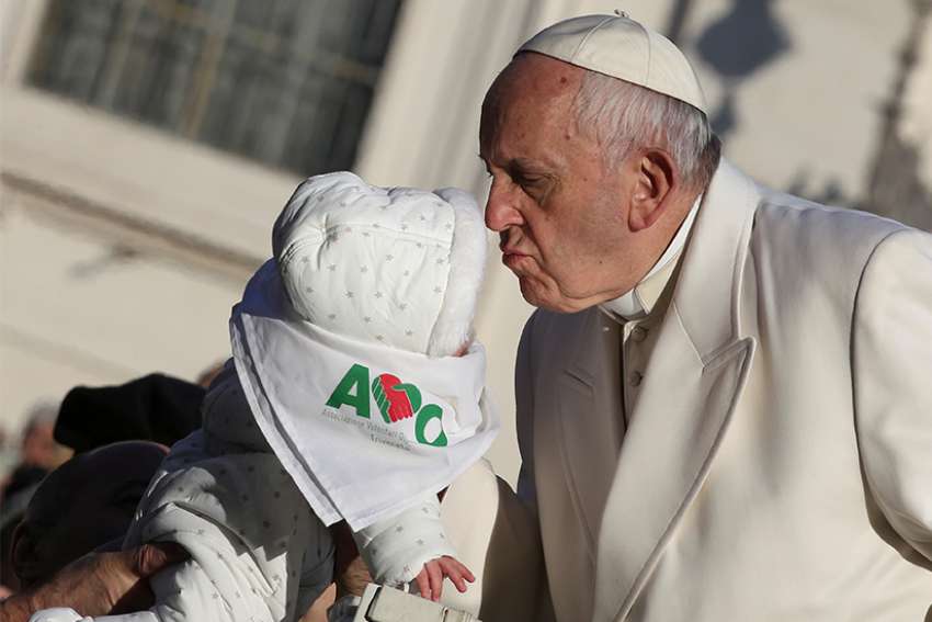 Pope Francis kisses a baby as he arrives for his general audience Jan. 24 in St. Peter&#039;s Square at the Vatican.