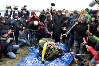 Journalists gather around a piece of a meteorite, according to local authorities and scientists, after it was pulled from the bottom of Russia&#039;s Chebarkul Lake in 2013.