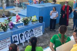 A group of pilgrims gathers near the tomb of Maryknoll Sisters Ita Ford and Maura Clarke Dec. 1, the eve of the 40th anniversary of their assassination in El Salvador. Along with Ursuline Sister Dorothy Kazel and laywoman Jean Donovan, the Maryknoll sisters helped children and civilians find refuge, but were subsequently raped and assassinated by military.