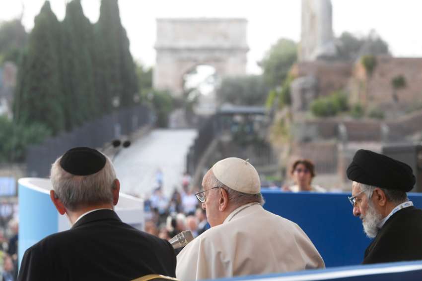 Pope Francis reads his speech at an interreligious meeting for peace at Rome&#039;s Colosseum Oct. 25, 2022. In the distance are the ruins of the Roman Forum.