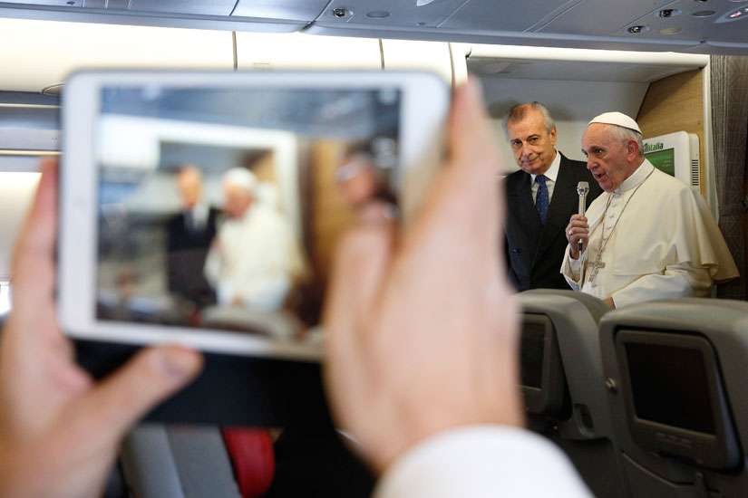 A journalist takes a photo on a tablet as Pope Francis speaks to journalists aboard his flight from Rome to Nairobi, Kenya, Nov. 25. The pope is visiting Kenya, Uganda and the Central African Republic during his six-day African tour.