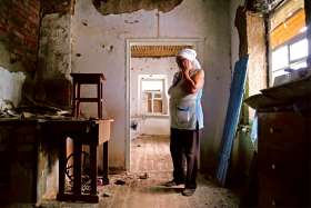 Katerina Izvekova, 77, reacts inside her home damaged during a military conflict between militants of the self-proclaimed Donetsk People’s Republic and the Ukrainian armed forces in late July.