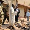 A priest and security forces look over the scene of a car bomb explosion at St. Theresa Catholic Church in Madalla, just outside Nigeria&#039;s capital Abuja, Dec. 25. The explosion at St. Theresa&#039;s killed at least 27 people.