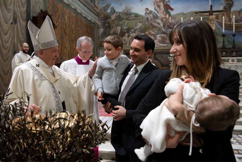 Pope Francis greets a child as he baptizes one of 32 babies as he celebrates Mass on the feast of the Baptism of the Lord in the Sistine Chapel at the Vatican Jan. 12, 2020.