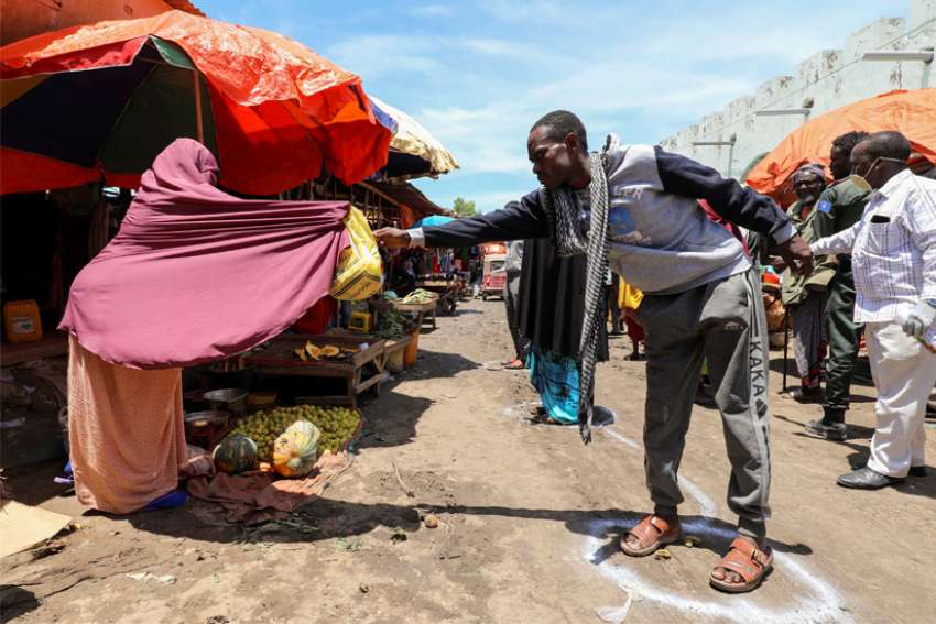 A Somali woman sells fruits to a customer standing at a social distancing marker in late April in Mogadishu, Somalia, during the COVID-19 pandemic.