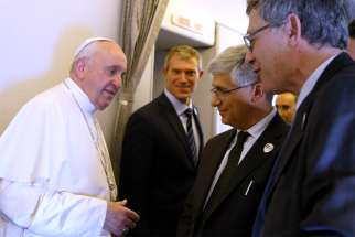 Pope Francis talks with Paolo Ruffini, right, head of the Vatican Dicastery for Communication, and Andrea Tornielli, editorial director of the same dicastery, aboard his flight from Rome to Abu Dhabi, United Arab Emirates, Feb. 3, 2019. Looking on is Matteo Bruni of the Vatican Press Office who was recently appointed as director of that office. The Vatican has been working to streamline and coordinate its varied communications entities.