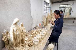 A woman works on a small statue of Pope Francis at the workshop of Ecuadorean sculptor Ramon Guato in Quito June 12. Guato, a sculptor of religious figures, has prepared about 2,000 figures to be sold at Catholic libraries ahead of the upcoming visit by Pope Francis to Ecuador in July. 
