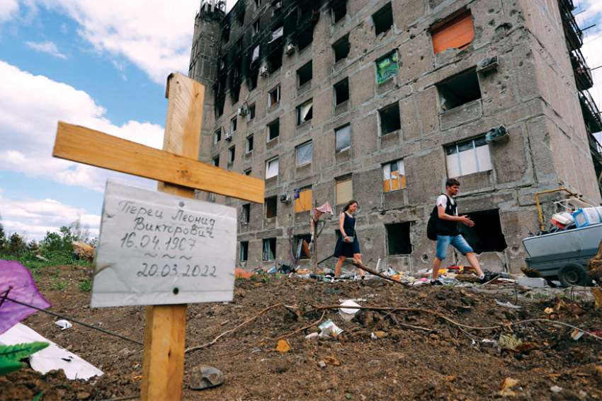 A grave of a civilian killed during Russian attacks on Mariupol, Ukraine, is seen next to a damaged apartment building April 28.