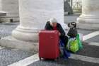A homeless woman sits with her belongings as she waits for a friend leaving the Vatican following a March 26 visit. 