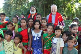 Syro-Malankara Bishop Jacob Barnabas Aerath and Msgr. John E. Kozar, head of the Catholic Near East Welfare Association, pose with village children during a visit to northeast India in late November.