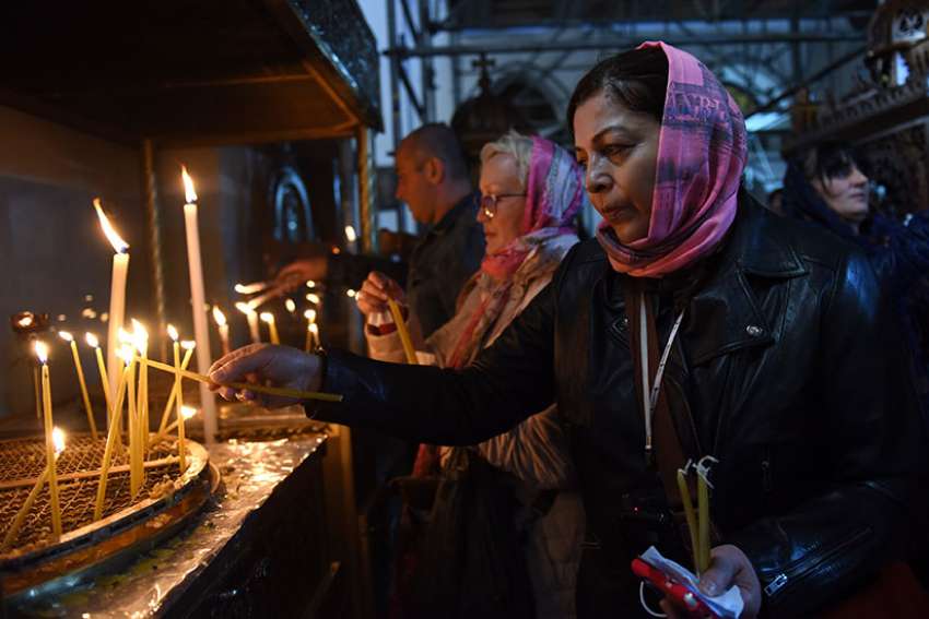 A pilgrim lights a candle Dec. 17 in the grotto of the Church of Nativity in Bethlehem, West Bank.