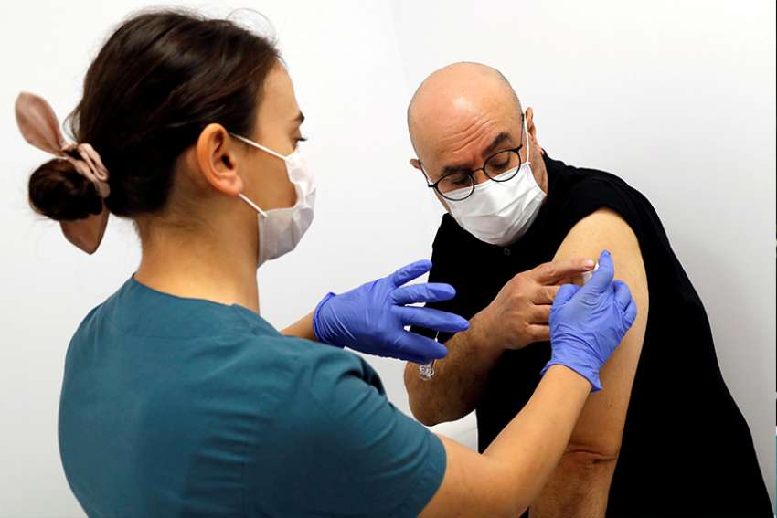 A health worker injects a volunteer with an experimental COVID-19 vaccine during Phase III trials in late September at a hospital in Kocaeli, Turkey. In an interview with a Spanish magazine, Pope Francis said a potential vaccine for COVID-19 belongs to all of humanity and must not &quot;be the property of the country of the laboratory that discovered it or of a group of countries that were allied for this.&quot;