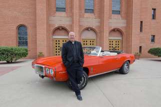Father Matthew Keller, rector of Sacred Heart Cathedral in Gallup, N.M., poses June 8 with a 1969 Pontiac Firebird Convertible that he refurbished for a raffle in support of vocations for the Diocese of Gallup.