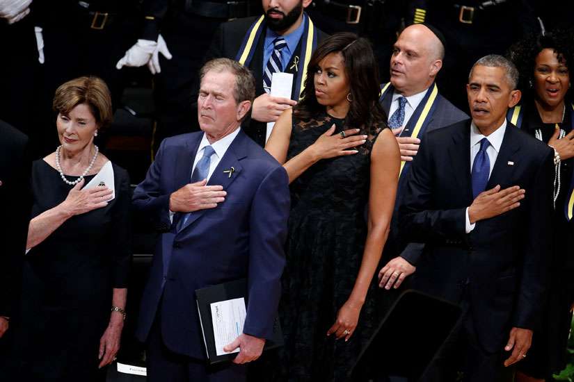 Former first lady Laura Bush, former U.S. President George W. Bush, first lady Michelle Obama and President Barack Obama hold their hands on their hearts as they sing the national anthem July 12 at a memorial service held in honor of police officers killed and wounded in shootings in Dallas.
