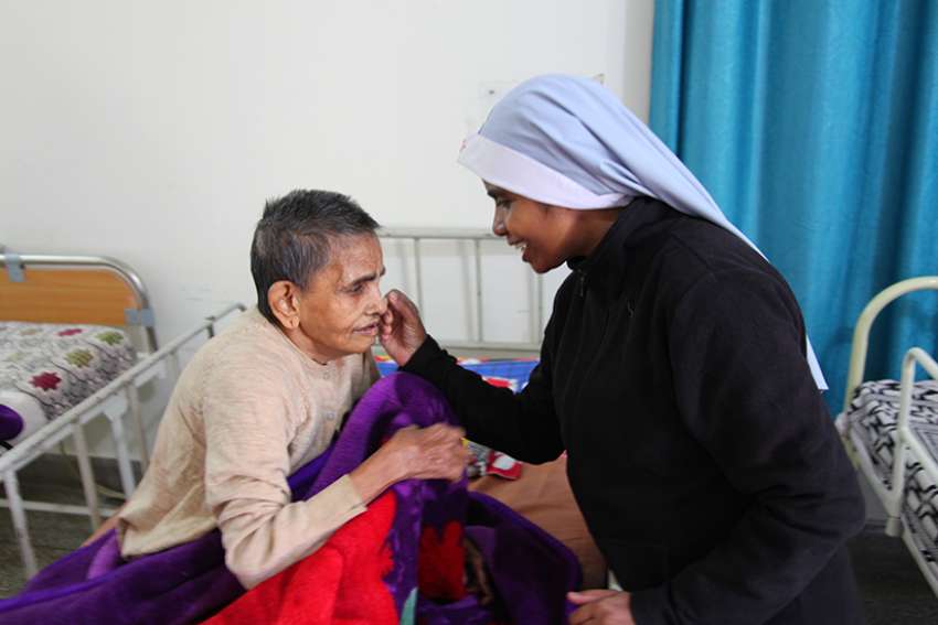 A religious sister is seen comforting a sick woman in 2016 at Snehadam Old Age Home in Gurgaon, India. 