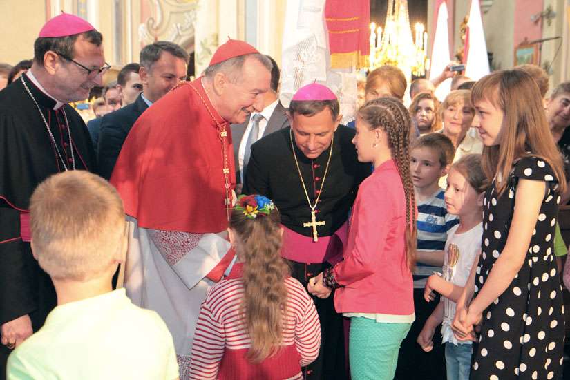 Cardinal Pietro Parolin, Vatican secretary of state, in red vestments, greets young people during a June 18 visit to Lviv, Ukraine. Although his visit included meetings with the state officials, church leaders and religious communities, Cardinal Parolin said the main purpose was to express the solidarity with people suffering from the war in the east.