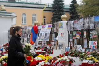  A woman holds flowers while standing next to a makeshift memorial outside the Armenian embassy in Moscow Oct. 20, 2020. The memorial was for people killed during a military conflict over the breakaway region of Nagorno-Karabakh.