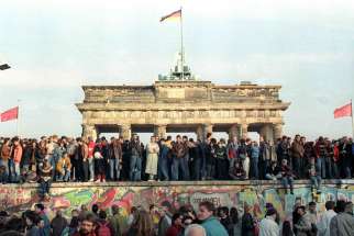 People stand atop the Berlin Wall in front of the Brandenburg Gate in this Nov. 10, 1989, file photo. Catholic bishops from the European Union marked 30 years since the breaching of the Berlin Wall with tributes to those who worked for peaceful change, as well as warnings against resurgent &quot;ideologies behind the building of walls.&quot;